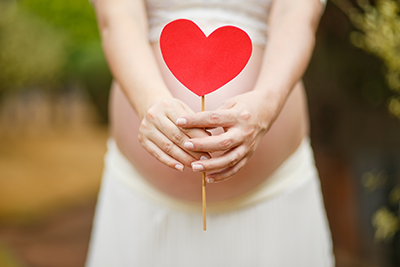 prenant woman holding heart lollipop over belly